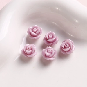 Detalle macro de cinco cuentas de rosa de resina lavanda para joyería DIY y uñas