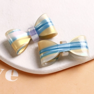 Detail of colorful acetate hair bow accessories with stripes on white stone surface
