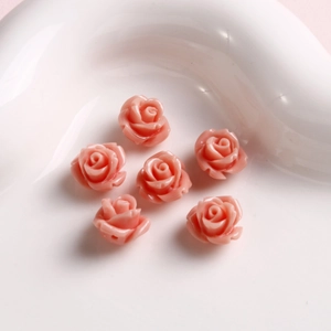 Vista macro de 6 cuentas de rosas rosadas con agujeros para joyería hecha a mano