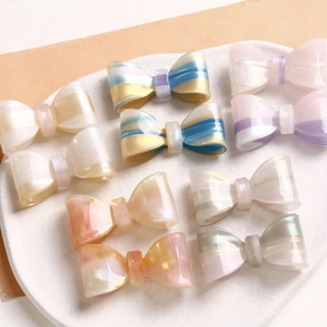 Colorful translucent acetate bow hair clips in assorted macaron shades on a white plate