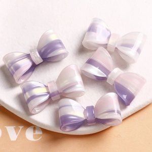 Close-up of five iridescent purple and white striped resin bow-knot hair accessories