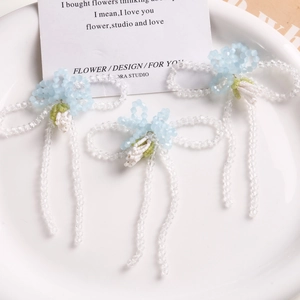 Detailed shot of handmade blue and clear beaded glass bow accessories on white porcelain