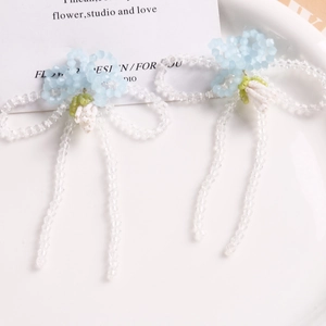 Handmade woven flower and glass bow earrings with long beaded tassels in light blue