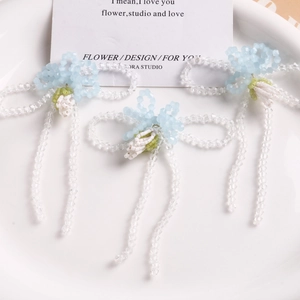 Detail of handcrafted blue and clear glass beaded bow flower charms for jewelry making