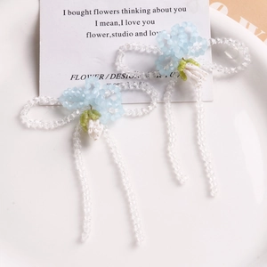 Macro shot of handmade light blue beaded flower earrings with long clear bead streamers