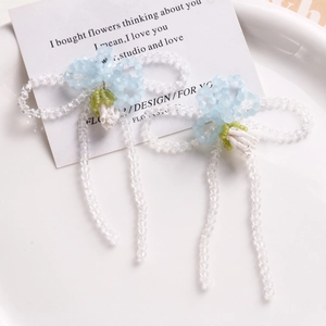 Detail of handmade beaded bow earrings with blue and white beads on a white ceramic plate