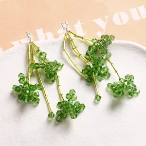 Boucles d'oreilles pompons en perles de cristal vert avec tubes en verre sur céramique