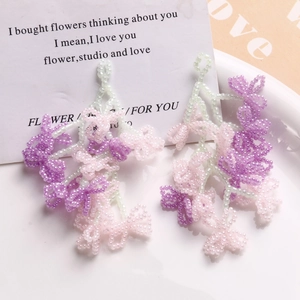 Handmade beaded floral tassel earrings in soft pink and purple tones with green accents