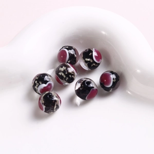 Makroaufnahme von 10mm Lampwork-Glasperlen in Schwarz und Burgund mit Wellenmustern