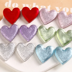 Macro detail of heart-shaped resin charms with silver foil texture on marble tray