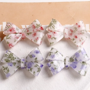 Floral bow hair clips set with pink and purple blossoms in a ceramic tray