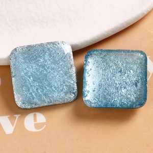 Macro detail of square resin earrings with blue cracked texture and glitter mica flakes