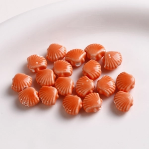 Macro shot of 12mm orange shell-shaped ceramic beads for DIY jewelry making in a dish