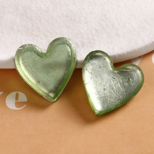 Macro view of two light green heart resin charms with silver foil texture detail