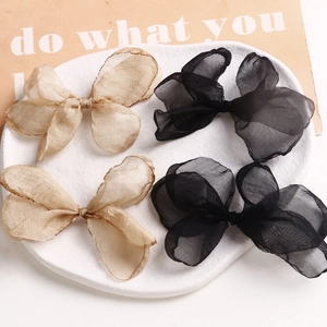 Eleganti fiocchi per capelli in organza oro e nero posati su un piatto di ceramica bianca