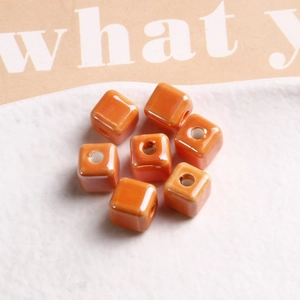 Close-up of glossy orange 9mm cubic ceramic beads with center hole for DIY jewelry