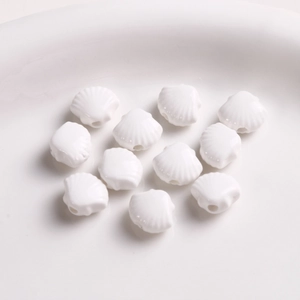Macro view of white fan-shaped shell ceramic beads with hole for DIY jewelry making