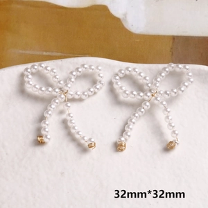Dettaglio di fiocchi in perle bianche fatti a mano con filo dorato per gioielli DIY