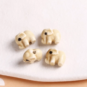 Close-up of four cream ceramic elephant beads with pre-drilled holes for DIY jewelry