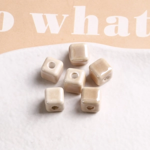 Macro view of 9mm beige square glazed ceramic beads with central hole for DIY jewelry