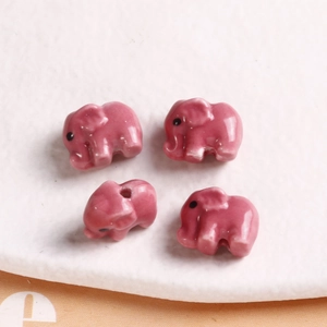 Detailed view of four pink ceramic elephant beads with glossy glaze for DIY jewelry making
