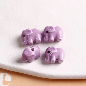 Macro view of four light purple elephant-shaped ceramic beads for DIY jewelry making