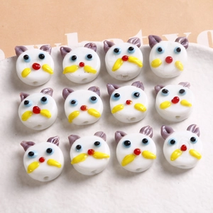 Detailed view of twelve handmade cat-shaped glass beads for creative DIY jewelry crafts