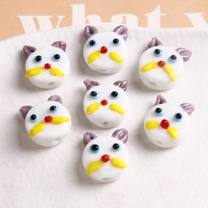 Macro detail of handmade white glass cat beads with colorful facial details for DIY jewelry
