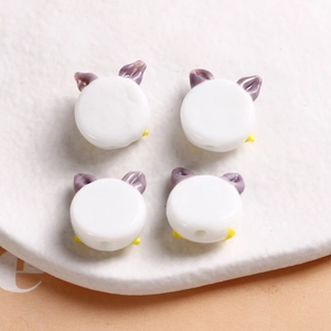 Close-up of four handmade cartoon glass beads for DIY jewelry making in purple and white