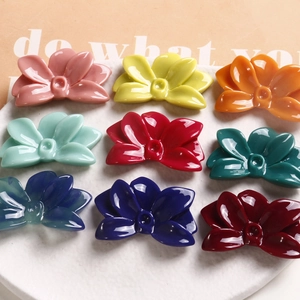 Nine colorful glossy flower-shaped resin hair clips arranged on a white tray