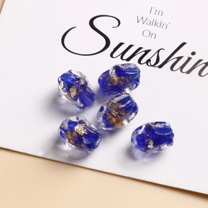Dettaglio di cinque perline di vetro blu scuro con foglia d'oro per gioielli fai-da-te