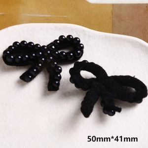 Dettaglio dei fiocchi neri con perline e floccati con dimensioni 50 mm per 41 mm