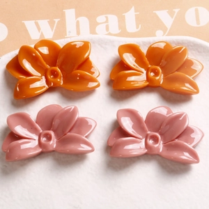 Detailed view of glossy resin flower charms in bright orange and soft dusty pink colors