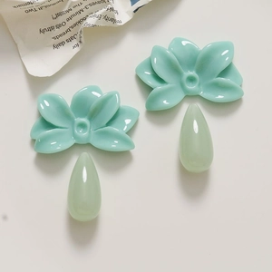 Detailed view of mint green resin flower charms and matching water drop pendants for DIY jewelry