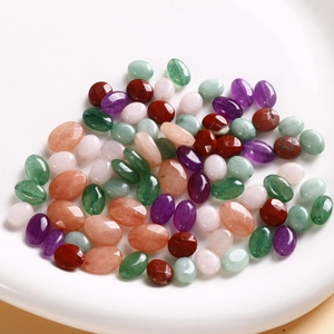 Polished oval natural semi-precious stone beads including amethyst and aventurine on a tray