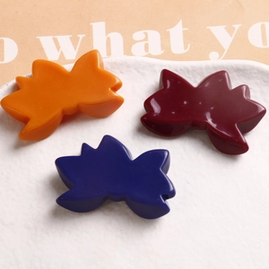 Chic resin butterfly hair clips in orange, wine red, and navy on a white ceramic tray