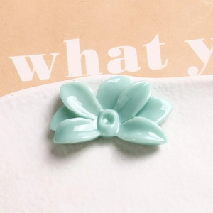 Macro view of mint green resin flower charm with a glossy finish and five-petal design