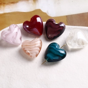 Vista macro di perle di vetro colorate a forma di cuore e perno in metallo per DIY