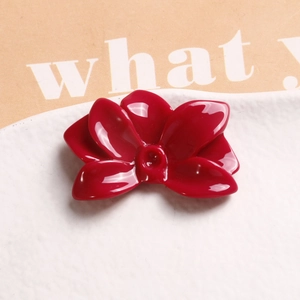 Close-up of deep red resin flower accessory with glossy finish on a ceramic tray
