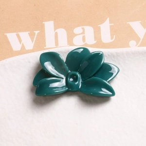 Top view of dark green resin flower accessories on a white plate with glossy finish