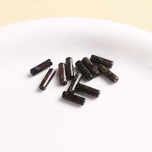 Macro shot of cylindrical natural stone beads with green and red marble patterns
