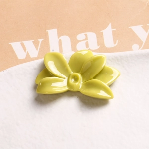 Close-up of a light green glossy resin flower charm for DIY jewelry on a white plate