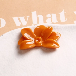 Macro shot of glossy orange flower resin accessory on minimalist textured background