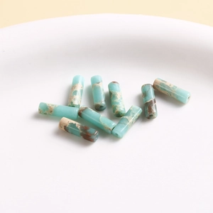 Macro shot of turquoise blue cylindrical tube beads with marble texture in a ceramic tray