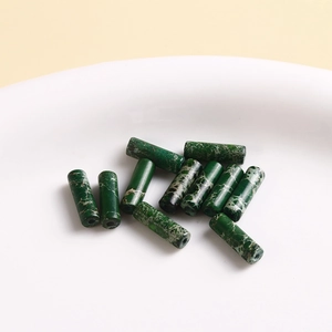 Close-up of dark green natural stone cylinder beads with marble texture for DIY jewelry