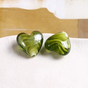 Dettaglio di perle a cuore in vetro verde e bianco con spirale per gioielli fai-da-te