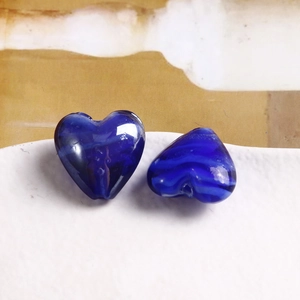 Dettaglio di perline in vetro a cuore blu scuro con texture interna per gioielli fai-da-te