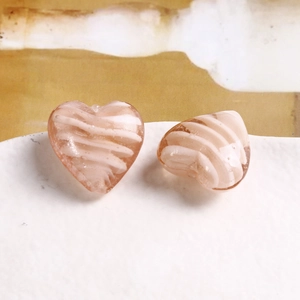 Dettaglio di una perla in vetro a cuore rosa con spirali bianche per gioielli fai da te