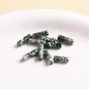 Macro detail of cylindrical natural stone beads with green and white marble texture