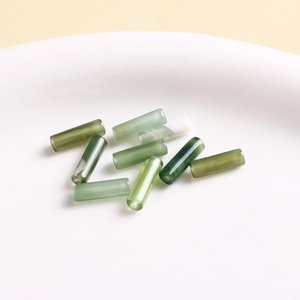 Macro view of natural green stone cylindrical beads with crackle textures for DIY jewelry